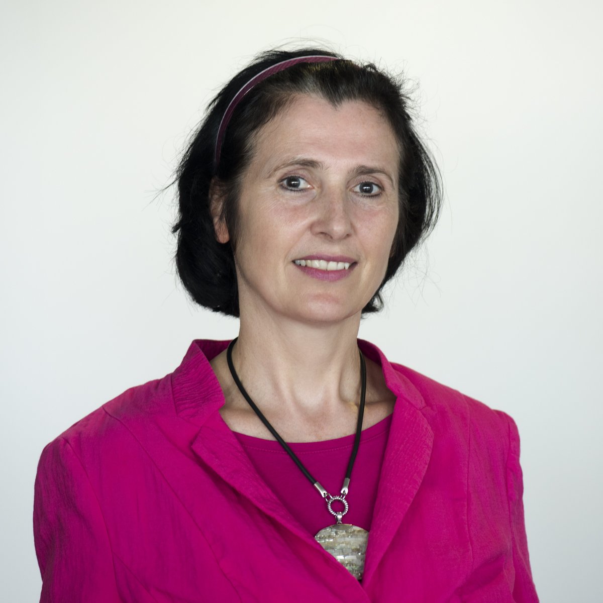 black-haired woman in front of a white wall