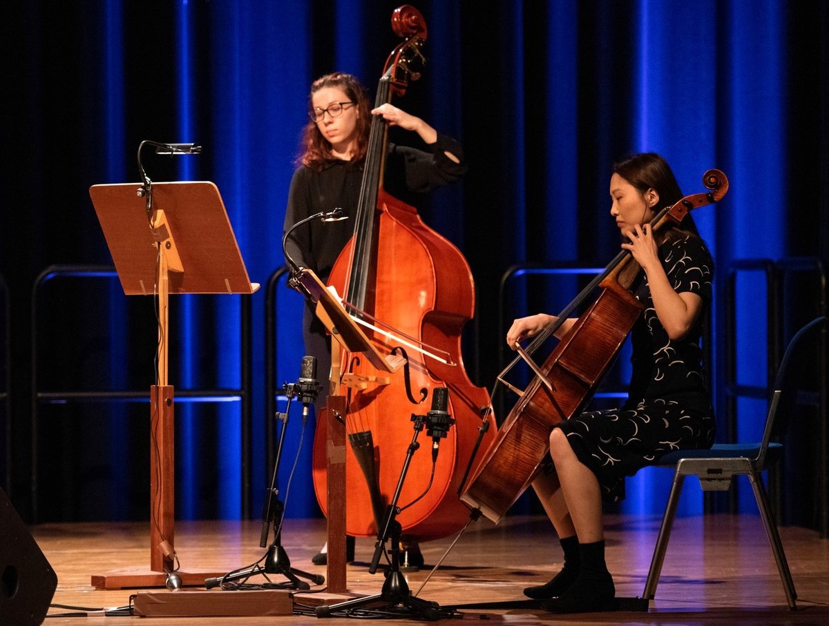 Two students with string instruments.