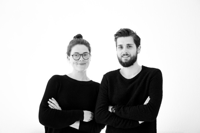 Architektur Absolventen Maria Constanze Hutter und Marc Timo Berg in schwarzer Kleidung vor weißem Hintergrund