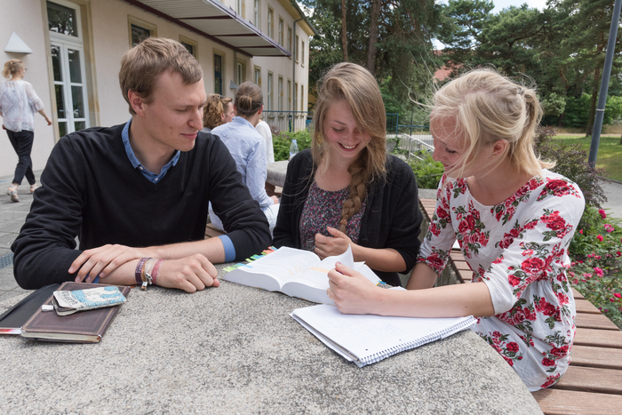 Drei Studierende sitzend an einem Tisch