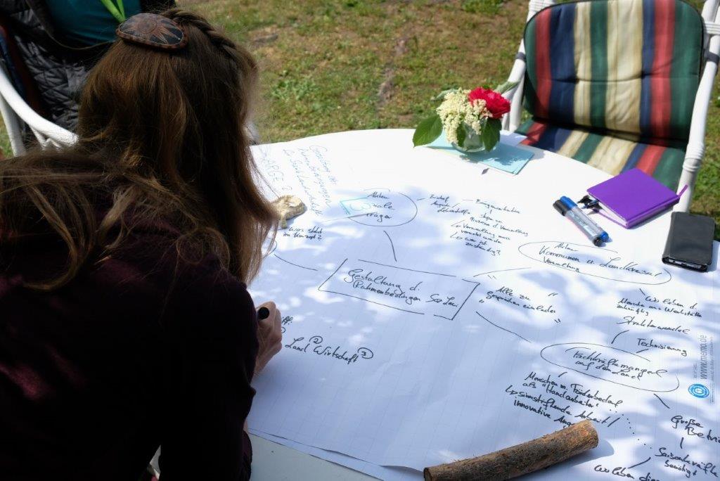 A woman works on a document spread out on a table in front of her.