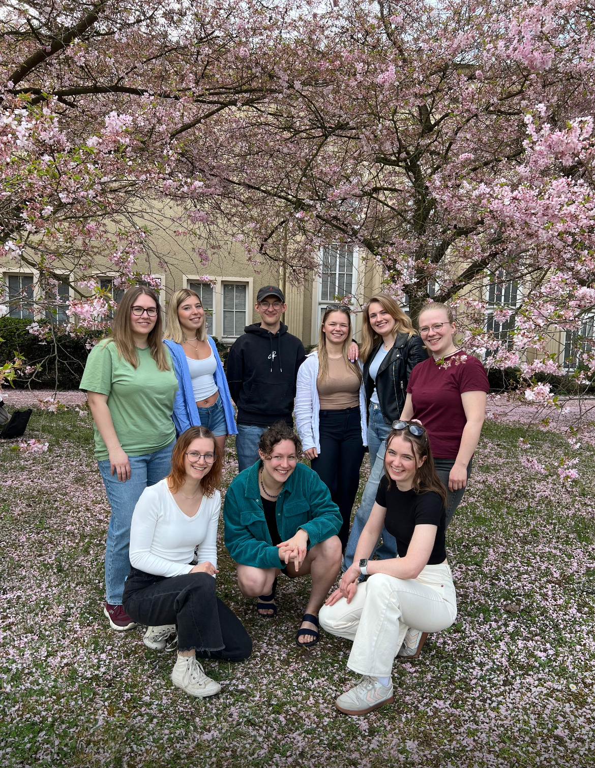 Das Foto zeigt die Studierenden, die sich in im FSR Gesundheitswissenschaften engaieren vor blühenden Kirschbäumen auf dem Campus in Senftenberg. 