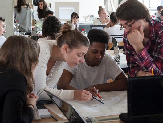 Das Fot zeigt Studierende bei einer gemeinsamen Arbeit am Tisch. 