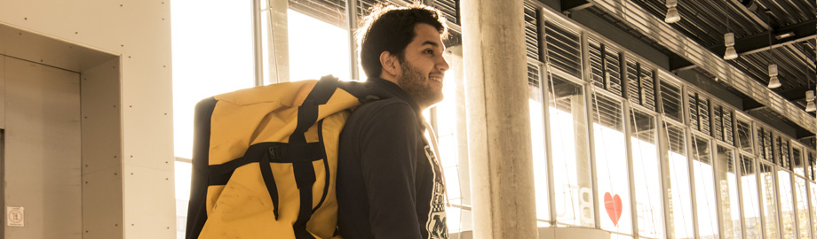 Das Banner von der Studierende ins Ausland Seite - Auf dem Bild steht ein Student mit einem Rucksack in einem BTU-Gebäude