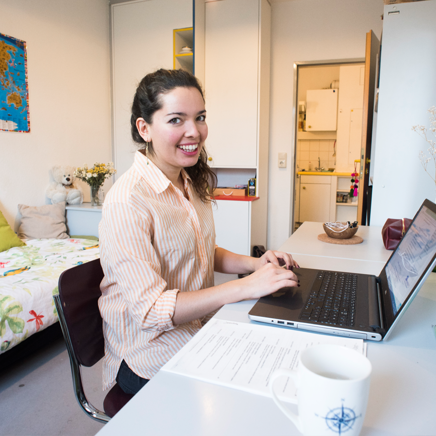 Auf dem Bild ist eine Studentin in ihrem Wohnheimzimmer zu sehen