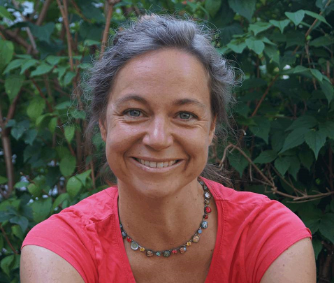 Christine Matt woman , smiling, in front of a greent hedge