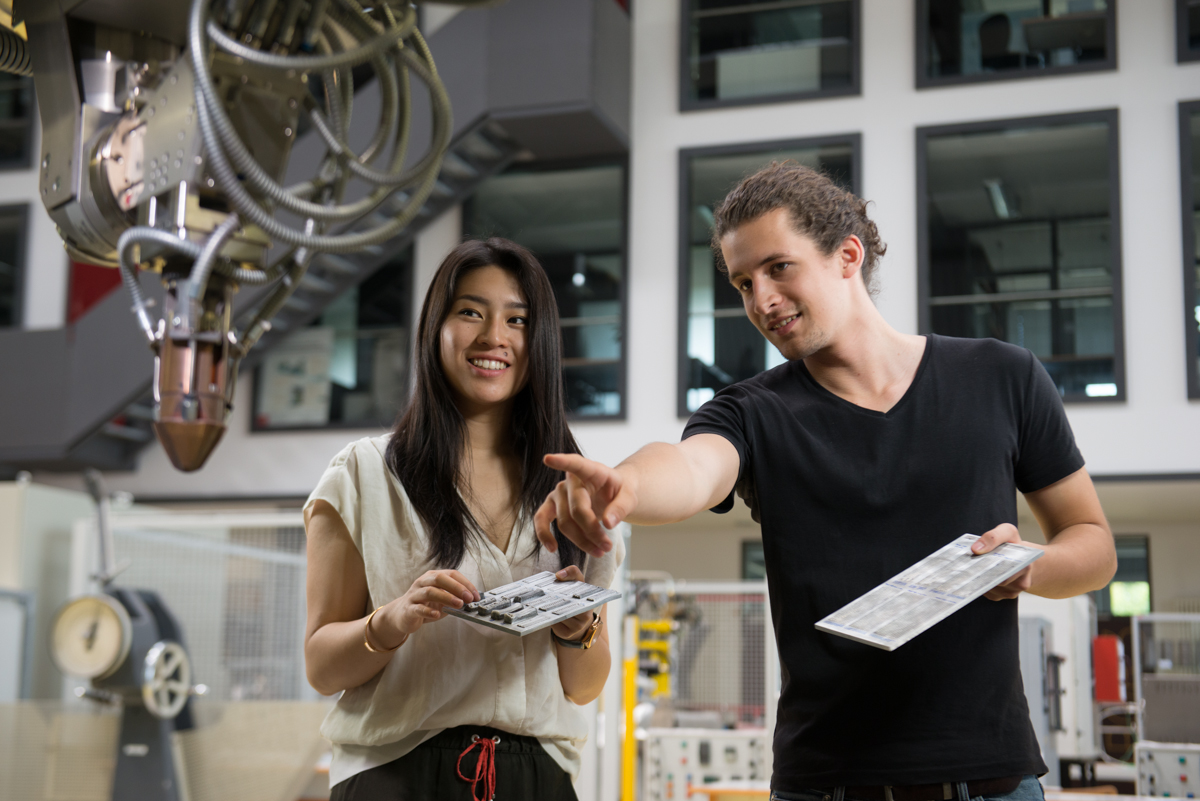 A female student and a male student at a laser welding machine....