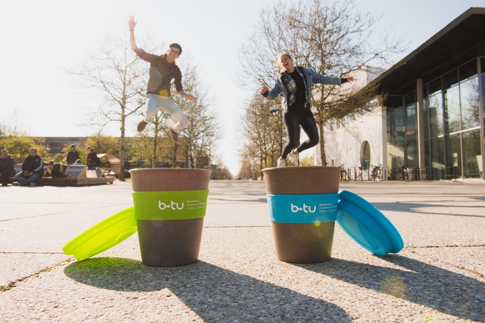 Kaffebecher und Studierende auf dem Zentralcampus