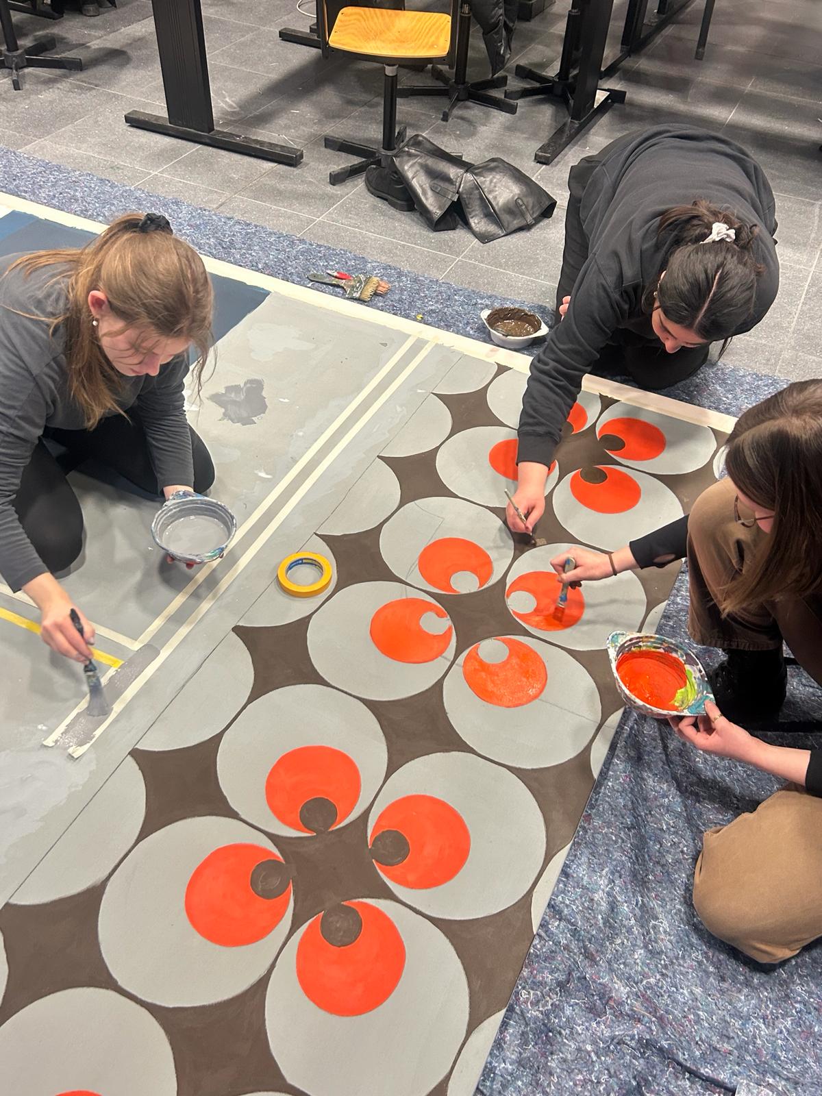 Students are painting large-scale works on the floor