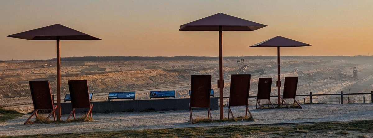 Umbrellas and deck chairs in front of open pit mine panorama