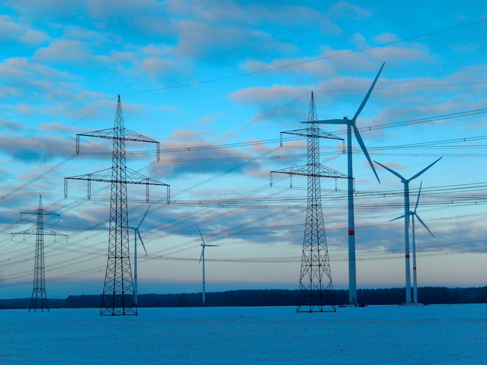 Windräder neben Strommasten symbolisieren die Energiewende und Energiesysteme der Zukunft