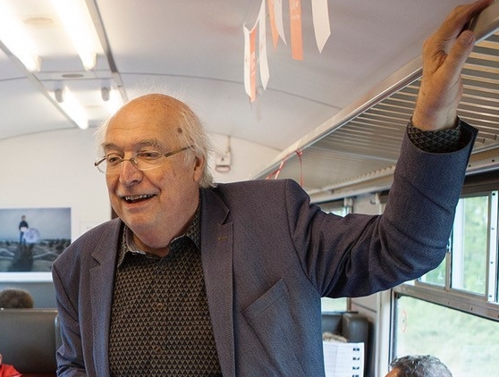 Ad van Liempt hält, in einem Eisenbahnabteil stehend, eien Vorlesung.