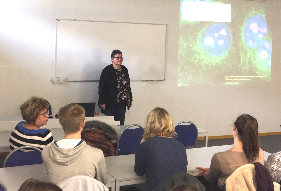 Die Studiengangsleiterin Dr. Barbara Hansen stellt den in einem Seminarraum sitzenden Jzgendlichen den Studiengang Biotechnologie vor.